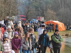 Tłum ludzi wśród nich policjanci oraz oznakowany radiowóz nad Zielonym Stawem w Kluczach. Podczas szkolenia z ratownictwa spod lodu. W tle widać namiot Straży Pożarnej.