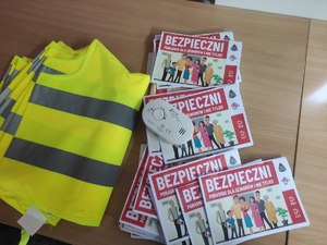 Kamizelki odblaskowe i broszury informacyjne „Bezpieczni –poradnik dla seniorów i nie tylko” a na nich czujka tlenku węgla.