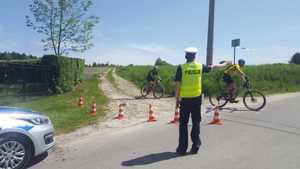 Policjant ruchu drogowego podczas przejazdu rowerowego wskazuje rowerzystom kierunek jazdy.