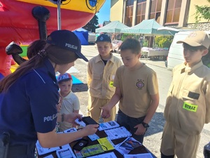 policjantka przy stoisku profilaktycznym pobiera odciski palców jednemu z dzieci