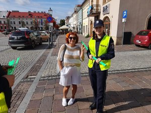 Policjantka wręcza odblask kobiecie. W tle olkuski rynek