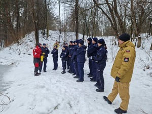 Policjanci stoją w szeregu przed ratownikiem GOPR. W tle krajobraz zimowy